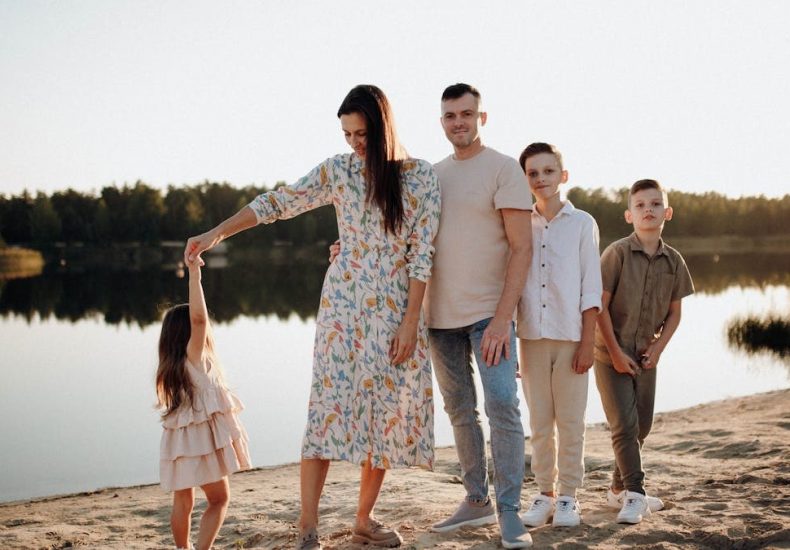 A family of five enjoys a serene lakeside vacation at sunset, capturing precious moments together.